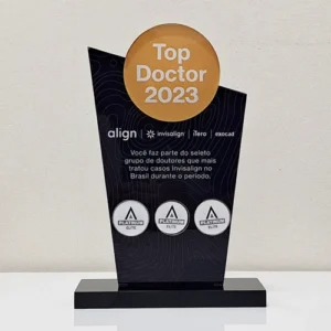 um troféu conquistado pela dra caroline como top doctor 2023 na cor preta com um disco dourado ao topo